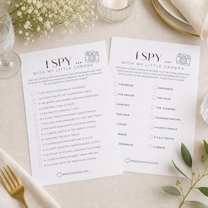 May include: Two white rectangular wedding game cards with black text and camera icons. The left card lists 15 I Spy tasks, while the right card features a checklist of wedding-themed items. Both cards include hashtag placeholders at the bottom.