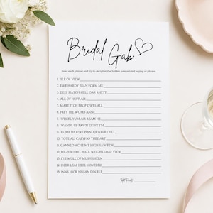 May include: A white rectangular game card titled Bridal Gab with a black heart icon. The card features fifteen numbered lines for a word puzzle game, with instructions to decipher love-related phrases. The text is printed in black ink.