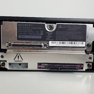 Peut inclure: Adaptateur réseau noir Sony pour la console PlayStation 2. L'appareil porte le numéro de série 1495678 et est étiqueté "SCPH-10281 MADE IN CHINA".