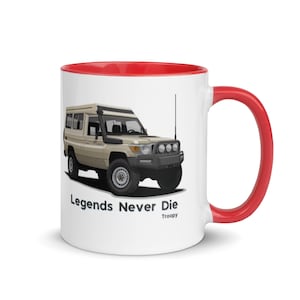May include: White ceramic mug with a red rim and handle. The mug features a cartoon illustration of a beige Toyota Land Cruiser with the text "Legends Never Die" and "Troopy" below the image.