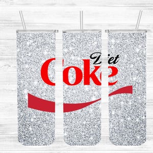 May include: A set of three silver glitter tumblers with the words "Diet Coke" in red and black. Each tumbler has a red wave design and a silver straw. The tumblers are designed to hold cold beverages.