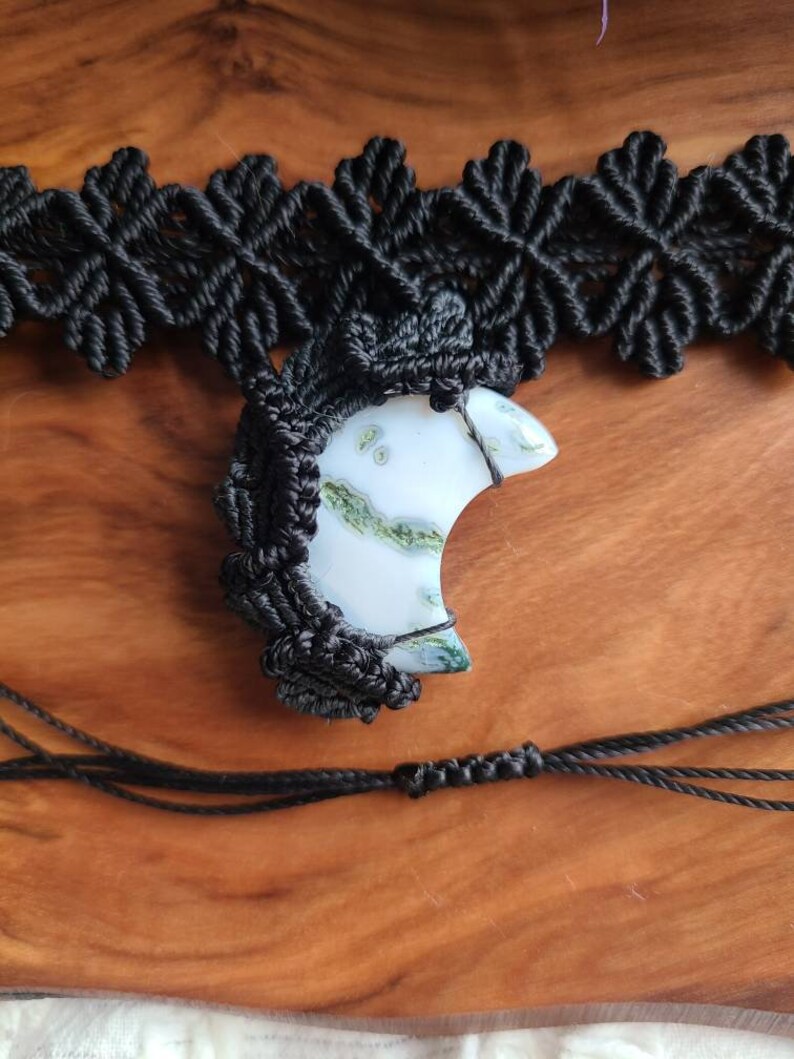 May include: A black macrame necklace with a crescent moon shaped green and white agate pendant.