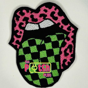 May include: Embroidered patch featuring a stylized mouth with pink leopard print lips and a green and black checkered tongue. The patch includes the text "The Patch Plug" in a neon green rectangle.