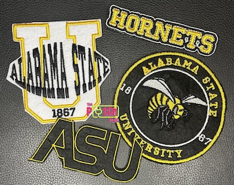 Può includere: Quattro toppe ricamate con il marchio della Alabama State University. Una toppa è una U bianca con testo nero, una è una toppa circolare nera con un calabrone giallo e nero, una è un logo ASU nero e una è una toppa con il testo Hornets giallo e nero.