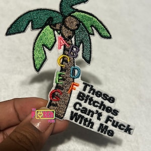 May include: Embroidered patch featuring a palm tree design with green fronds and a brown trunk. The patch includes the letters A through G in various colors and the text "These Bitches Can't Fuck With Me."