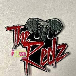 May include: Red and white embroidered patch with a black background. The patch features a stylized elephant with the text "The Redz" in red and white.