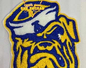 Può includere: Toppa ricamata con un disegno di bulldog in blu, giallo e bianco. La toppa ha un bordo giallo e include il testo "THAT'S WHAT SHE THREAD". Adatta per giacche, borse o altri articoli in tessuto.