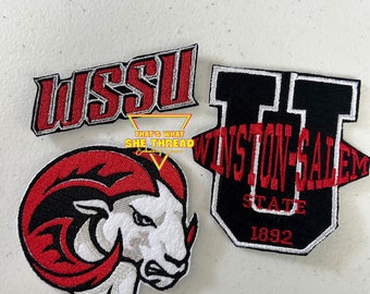 Puede incluir: Tres parches bordados con el logotipo de la Universidad Estatal de Winston-Salem. El primer parche es rojo y blanco y presenta la mascota de la escuela, un carnero. El segundo parche es negro y blanco y presenta las iniciales de la escuela, "WSSU". El tercer parche es negro y rojo y presenta el nombre completo de la escuela, "Winston-Salem State University", y el año 1892.