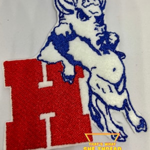 May include: Embroidered patch featuring a white buffalo with blue outlines, standing on top of a red letter "H". The patch has a white border and the text "That's What She Thread" in a colorful triangle below.