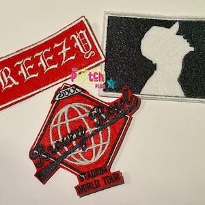 May include: Three embroidered patches. One red rectangular patch with the word "BREEZY" in white gothic lettering. A black and white patch with a baseball player silhouette. A red patch with "Bloozy Bowl Stadium World Tour" text.