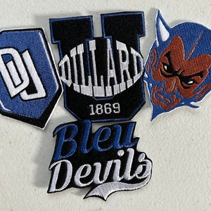 May include: Four embroidered patches, two blue, one black and white, and one brown and blue. The blue patches feature the letters "DJ" and "U", the black and white patch says "Bleu Devils", and the brown and blue patch features a devil's face. The "U" patch also says "Dillard 1869".