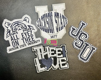 Può includere: Quattro toppe ricamate con il marchio della Jackson State University. Una toppa mostra una tigre con il testo ALL EYEZ ON THEE JACKSON STATE UNIVERSITY. Un'altra è a forma di U con JACKSON STATE 1877. Una dice THEE I LOVE con un cuore, e una dice JSU.