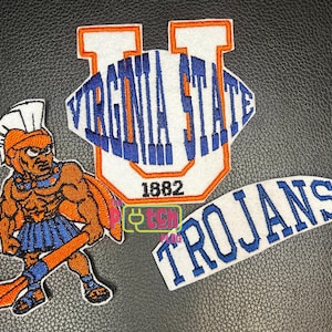 May include: Three embroidered patches featuring a white and orange U-shaped emblem with the text VIRGINIA STATE 1882 in blue, a warrior figure in orange and blue armor holding a spear, and a white curved patch with the blue text TROJANS.