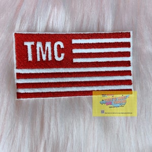 May include: Red and white embroidered patch with the letters "TMC" in white and five white stripes on a red background.