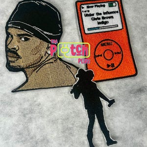 May include: Embroidered patches featuring a portrait, a music player, and a silhouette of a person. The portrait depicts a person wearing a black cap. The music player displays the song "Under the Influence" by Chris Brown. The patches are in shades of black, orange, and tan.