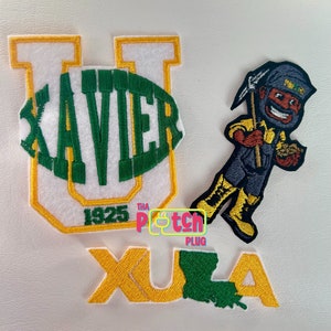 May include: Three embroidered patches. The first patch is white with a green oval that says "XAVIER" and a yellow outline. The second patch is yellow with the text "XULA" and a green outline. The third patch is a cartoon of a person with a pickaxe and a bag of gold. The person is wearing a blue shirt, blue overalls, and a yellow hat.