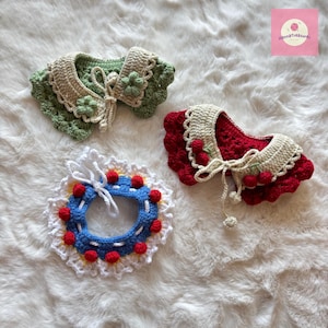 May include: Three handmade crochet collars in green, red, and blue. The green collar has a beige trim and flower accents. The red collar features a beige trim and cherry accents. The blue collar has a white trim and red dot accents. All collars have tie closures.