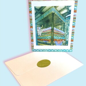 May include: A fairytale-themed greeting card showing a princess in a bed of many mattresses. The card has a decorative border and is accompanied by a cream envelope with a gold seal. The illustration depicts a canopy bed in a room.