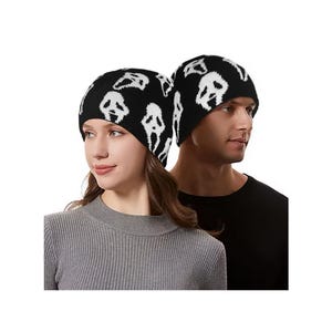 May include: Black knit beanie hats with a white ghost face pattern. The hats are worn by two people, one wearing a gray sweater and the other a black shirt. The hats are a stylish accessory.