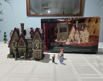 May include: A miniature model of a Victorian-style house with a dark gray roof and red brick accents. The house has a small fence and a tree in front of it. The house is part of a collection of literary classics.