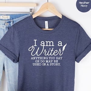 May include: A navy blue t-shirt with white text that reads "I am a Writer. Anything you say or do may be used in a story."