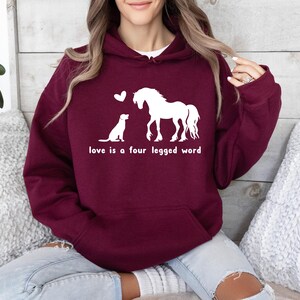 May include: A maroon hoodie with a white graphic of a horse and a dog with the text "love is a four legged word".