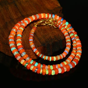 May include: A multi-strand necklace made of orange, white, and iridescent opal beads. The necklace is made of multiple strands of beads and has a gold clasp.