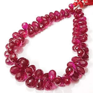 Peut inclure: Un brin de perles de pierres précieuses de couleur rouge rubis en forme de goutte. Les perles sont enfilées sur un fil fin et sont prêtes à être utilisées pour la fabrication de bijoux.
