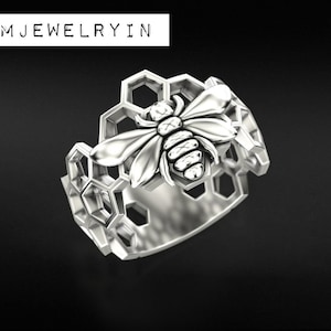 May include: A silver ring with a bee design set in a honeycomb pattern.