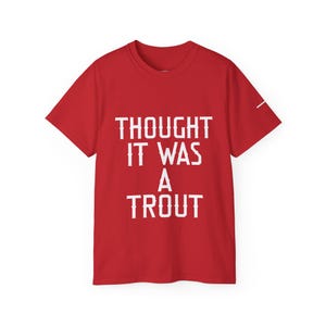 Może przedstawiać: Jaskrawoczerwony T-shirt z krótkim rękawem z białym napisem "THOUGHT IT WAS A TROUT" nadrukowanym pogrubioną, blokową czcionką na środku klatki piersiowej. Odzież posiada klasyczny okrągły dekolt oraz standardowy krój z krótkimi rękawami.