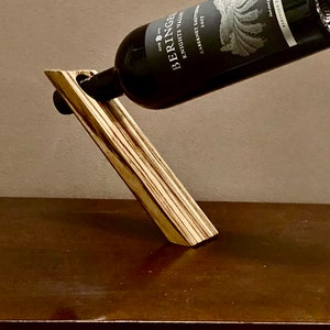 Puede incluir: Un soporte de madera para botellas de vino con un patrón a rayas. Una botella de vino Beringer Knights Valley Cabernet Sauvignon descansa en el soporte.