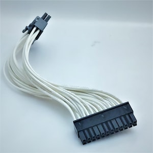Puede incluir: Un cable de alimentación de ordenador blanco de 24 pines con un conector negro.