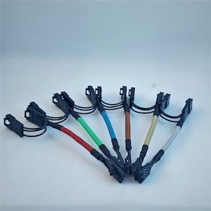May include: Six black and grey cables with different coloured sleeves. The sleeves are red, green, blue, brown, and gold. The cables are connected to black connectors at each end.