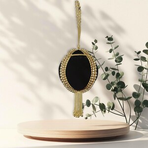 May include: A black velvet clutch bag with a gold chain strap and beaded trim. The bag has a tassel hanging from the bottom.
