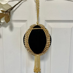 May include: A black velvet evening bag with a gold chain strap and tassel. The bag is decorated with gold beads and has a round shape.