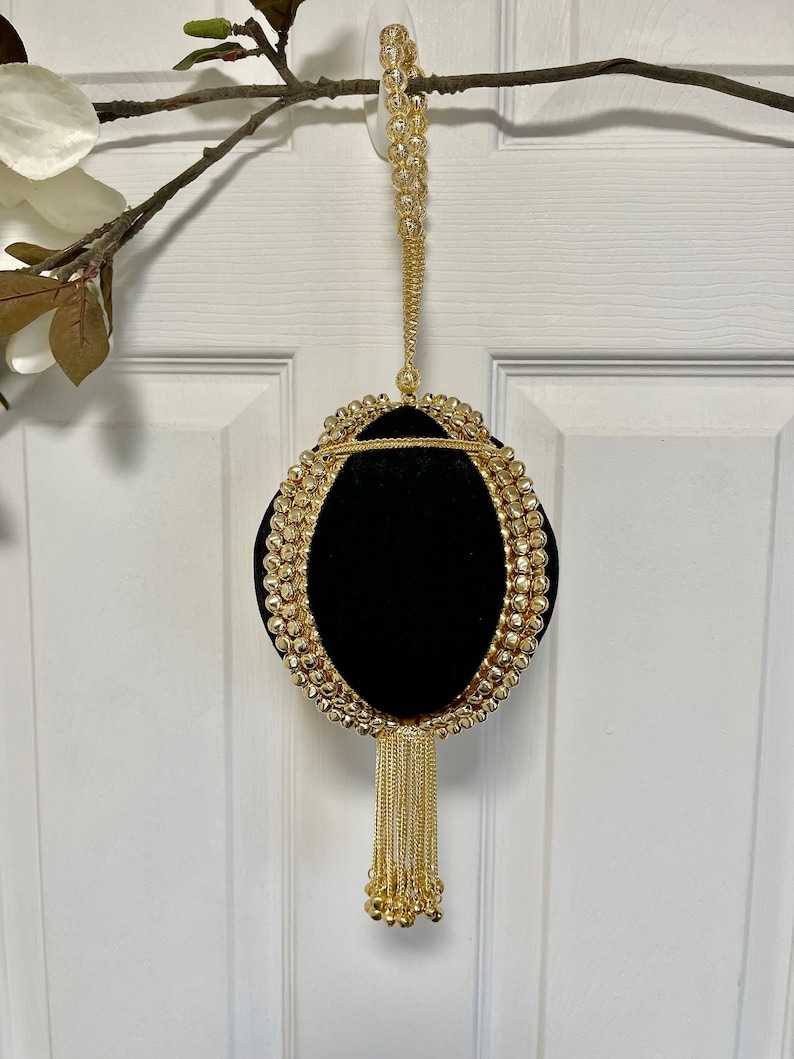 May include: A black velvet evening bag with a gold chain strap and tassel. The bag is decorated with gold beads and has a round shape.