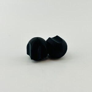 May include: Two black rubber earplugs, one with a smooth surface and the other with a textured surface.