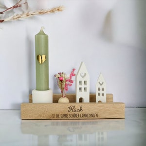 Peut inclure: Une &eacute;tag&egrave;re en bois avec une bougie verte, un petit vase avec des fleurs s&eacute;ch&eacute;es et deux maisons blanches. L'&eacute;tag&egrave;re porte la gravure "Gl&uuml;ck ist die Summe sch&ouml;ner Erinnerungen".
