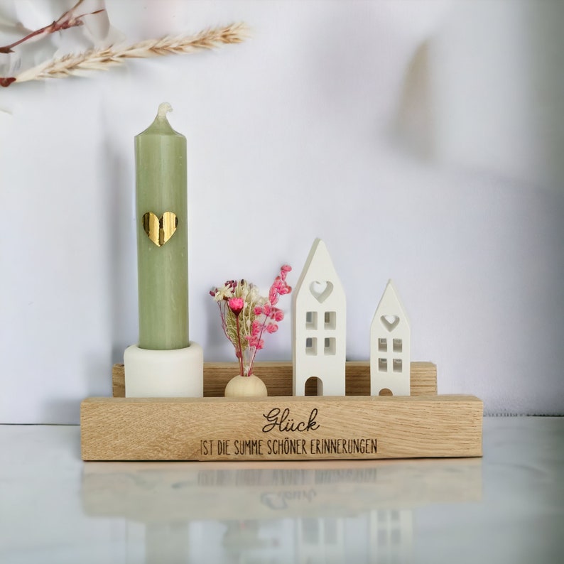 Peut inclure: Une &eacute;tag&egrave;re en bois avec une bougie verte, un petit vase avec des fleurs s&eacute;ch&eacute;es et deux maisons blanches. L'&eacute;tag&egrave;re porte la gravure "Gl&uuml;ck ist die Summe sch&ouml;ner Erinnerungen".