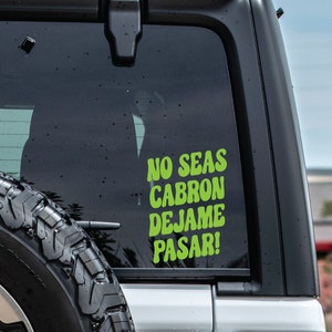 May include: A green and white sticker on the back window of a car that reads "No Seas Cabron Dejame Pasar!"