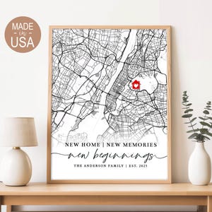 May include: A framed map print featuring a detailed black and white city map with a red house icon. The text reads "NEW HOME | NEW MEMORIES new beginnings THE ANDERSON FAMILY | EST. 2025". The print is in a wooden frame and is labeled "MADE - in - USA".