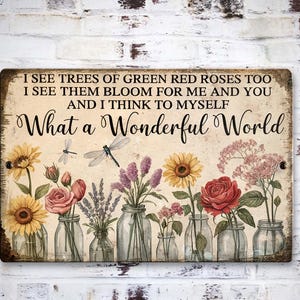 May include: A rectangular sign with the text "I SEE TREES OF GREEN RED ROSES TOO I SEE THEM BLOOM FOR ME AND YOU AND I THINK TO MYSELF What a Wonderful World." The sign features illustrations of flowers in glass jars, including sunflowers, roses, and lavender.