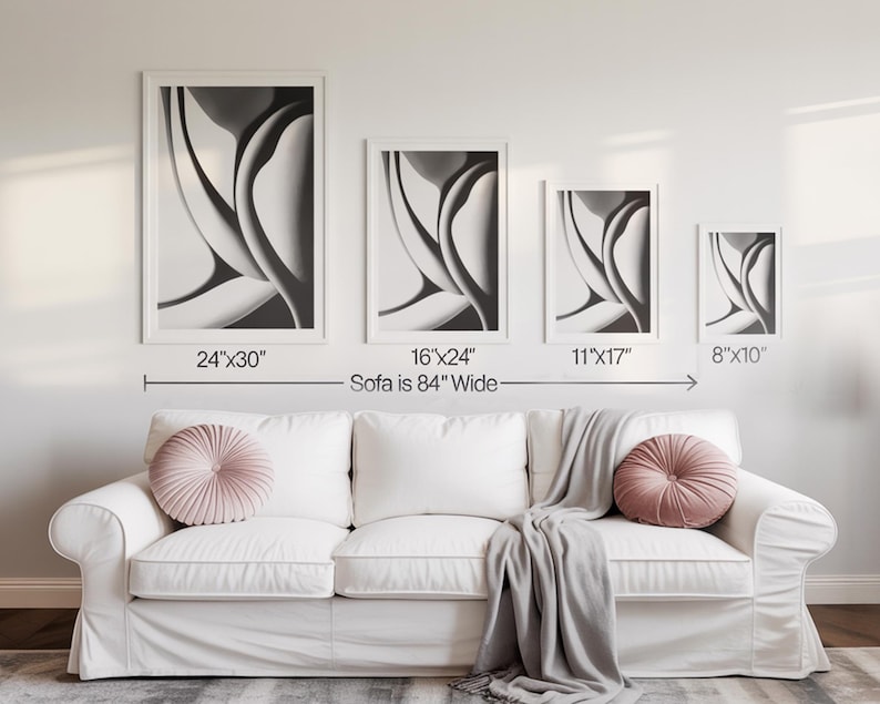 May include: Four framed abstract art prints in varying sizes, displayed above a white sofa. The prints are in black and white, with dimensions of 24"x30", 16"x24", 11"x17", and 8"x10". The sofa is 84 inches wide.