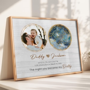 May include: A framed print with a light wood grain background. It features two circular images: a photo of a father and child, and a celestial map. Text includes "Daddy Jackson", coordinates, and "The night you became my Daddy."