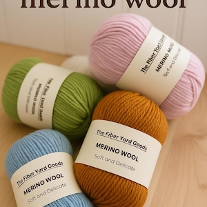 May include: A selection of merino wool yarn in various colours: pink, green, blue, and gold. Each skein has a label stating "The Fiber Yard Goods MERINO WOOL Soft and Delicate". The text "Super soft merino wool" is at the top.