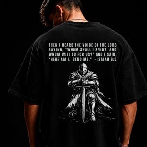 May include: A black t-shirt featuring a white graphic of a knight kneeling with a sword. Above the knight, the text reads: THEN I HEARD THE VOICE OF THE LORD SAYING, "WHOM SHALL I SEND? AND WHOM WILL GO FOR US?" AND I SAID, "HERE AM I. SEND ME." - ISAIAH 6:8
