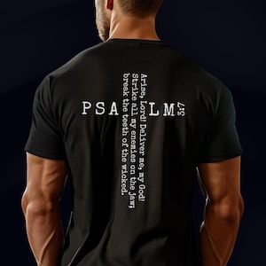 May include: A black short-sleeved t-shirt featuring white text arranged in a cross shape on the back. The text reads PSALM 3:7 and Arise, Lord! Deliver me, my God! Strike all my enemies on the jaw; break the teeth of the wicked in a distressed font.