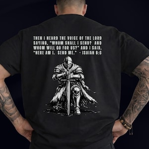 May include: A black t-shirt featuring a white graphic of a knight in armor kneeling and holding a sword. Above the knight, the text reads: THEN I HEARD THE VOICE OF THE LORD SAYING, "WHOM SHALL I SEND? AND WHOM WILL GO FOR US?" AND I SAID, "HERE AM I. SEND ME." - ISAIAH 6:8