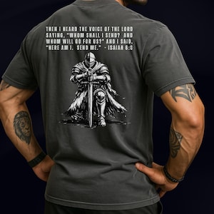 May include: A charcoal gray t-shirt featuring a white graphic of a knight kneeling with a sword. Above the knight, the text reads: THEN I HEARD THE VOICE OF THE LORD SAYING, "WHOM SHALL I SEND? AND WHOM WILL GO FOR US?" AND I SAID, "HERE AM I. SEND ME." - ISAIAH 6:8