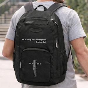 May include: Black backpack with multiple compartments, zippers, and mesh side pocket. The text "Be strong and courageous - Joshua 1:9" is printed on the front. The backpack is being worn by a person.